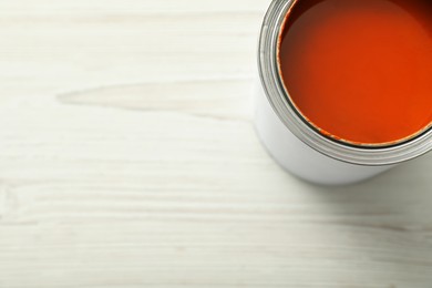 Photo of Can of orange paint on white wooden table, top view. Space for text