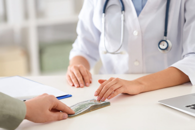 Patient giving bribe to doctor in clinic, closeup. Corrupted medicine