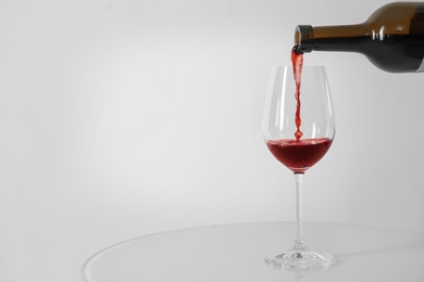 Photo of Pouring red wine into glass on white background