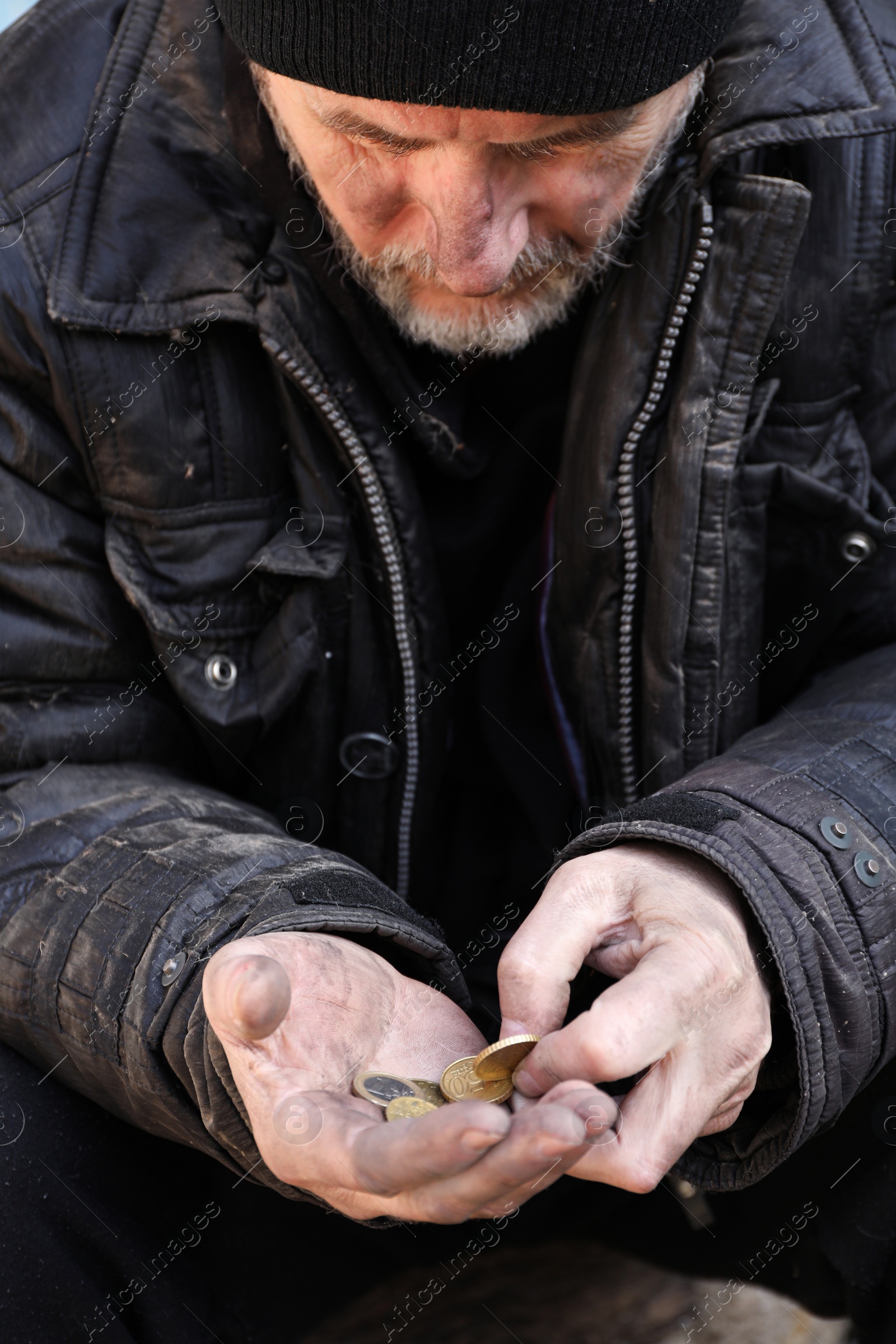 Photo of Poor homeless senior man holding coins outdoors