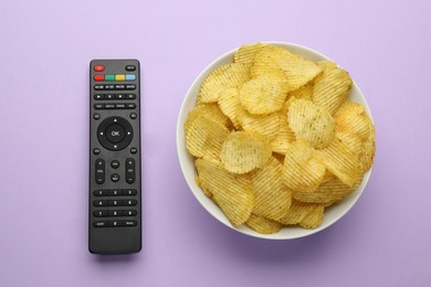 Photo of Remote control and bowl of potato chips on violet background, flat lay