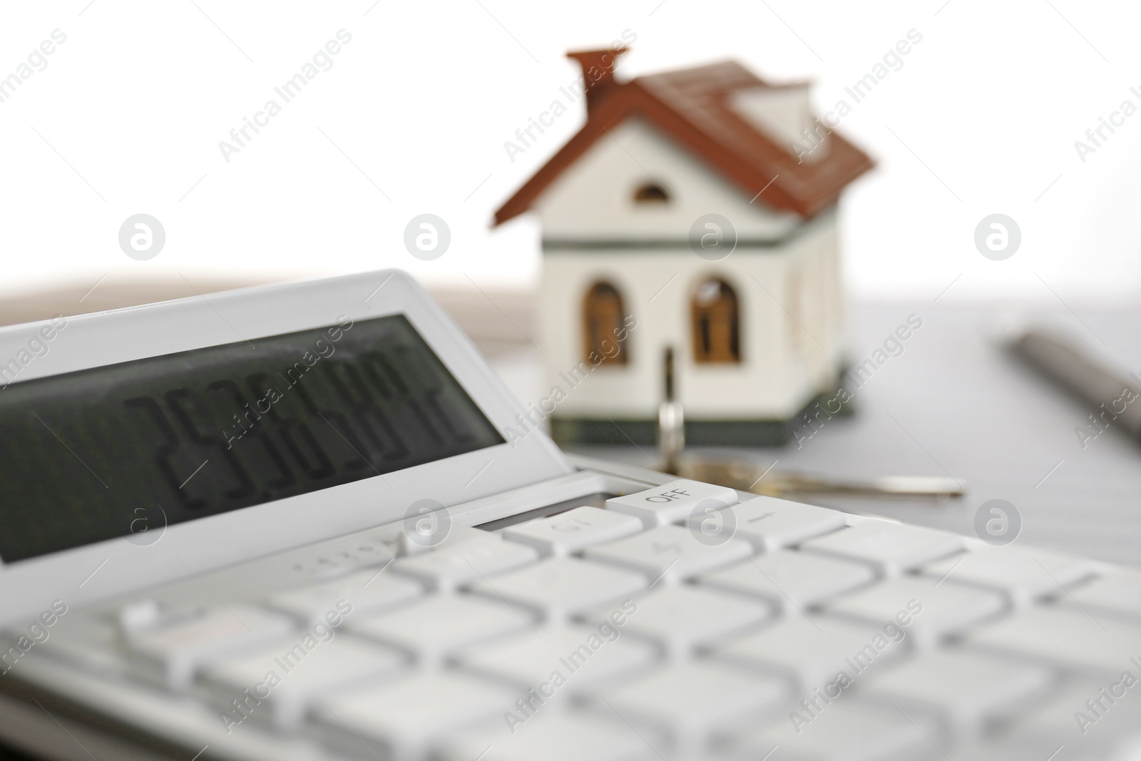 Photo of Calculator, house model and keys on table. Real estate agent's workplace