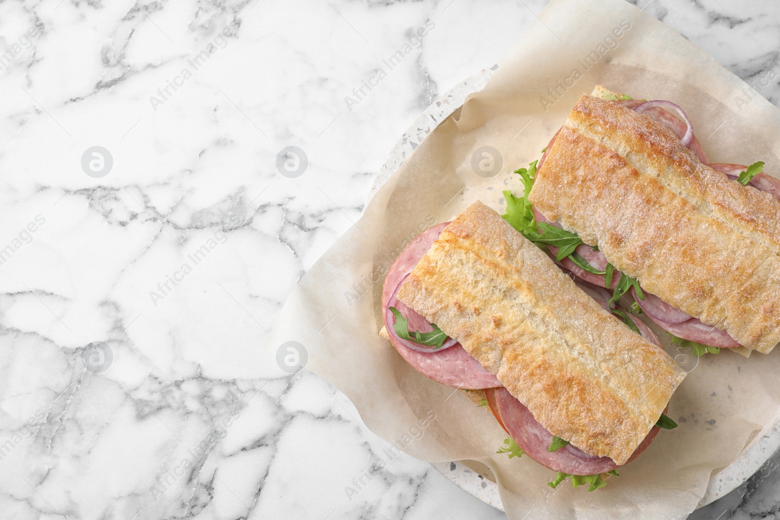 Photo of Tasty sandwiches with ham on white marble table, top view. Space for text