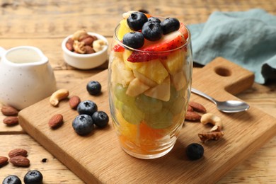 Photo of Delicious fruit salad, berries and nuts on wooden table