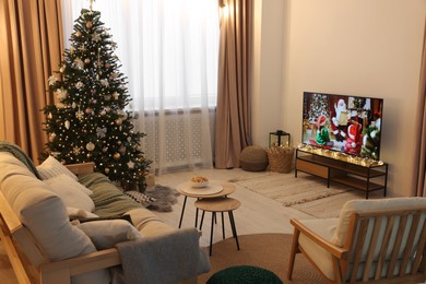 Photo of Wide TV set, furniture and Christmas tree in stylish room