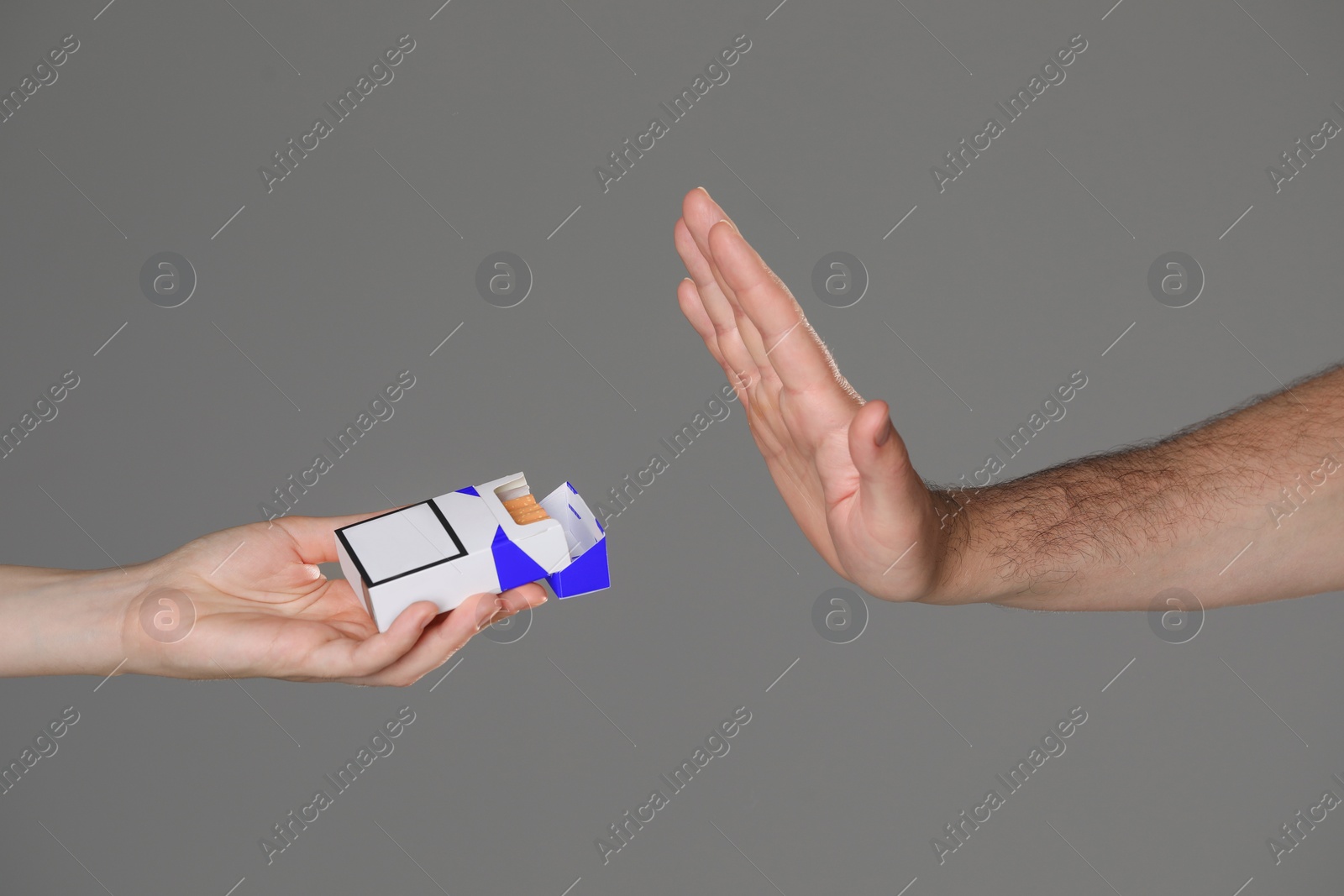 Photo of Stop smoking concept. Man refusing cigarettes on gray background, closeup