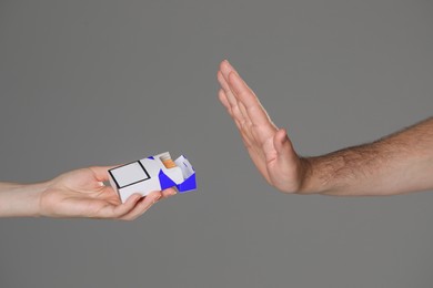 Stop smoking concept. Man refusing cigarettes on gray background, closeup