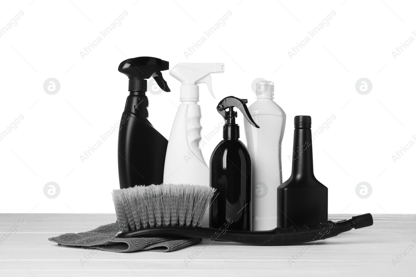 Photo of Bottles, brush and car wash cloth on wooden table against white background