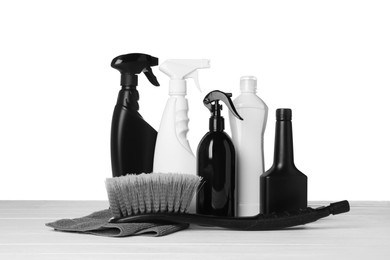 Photo of Bottles, brush and car wash cloth on wooden table against white background