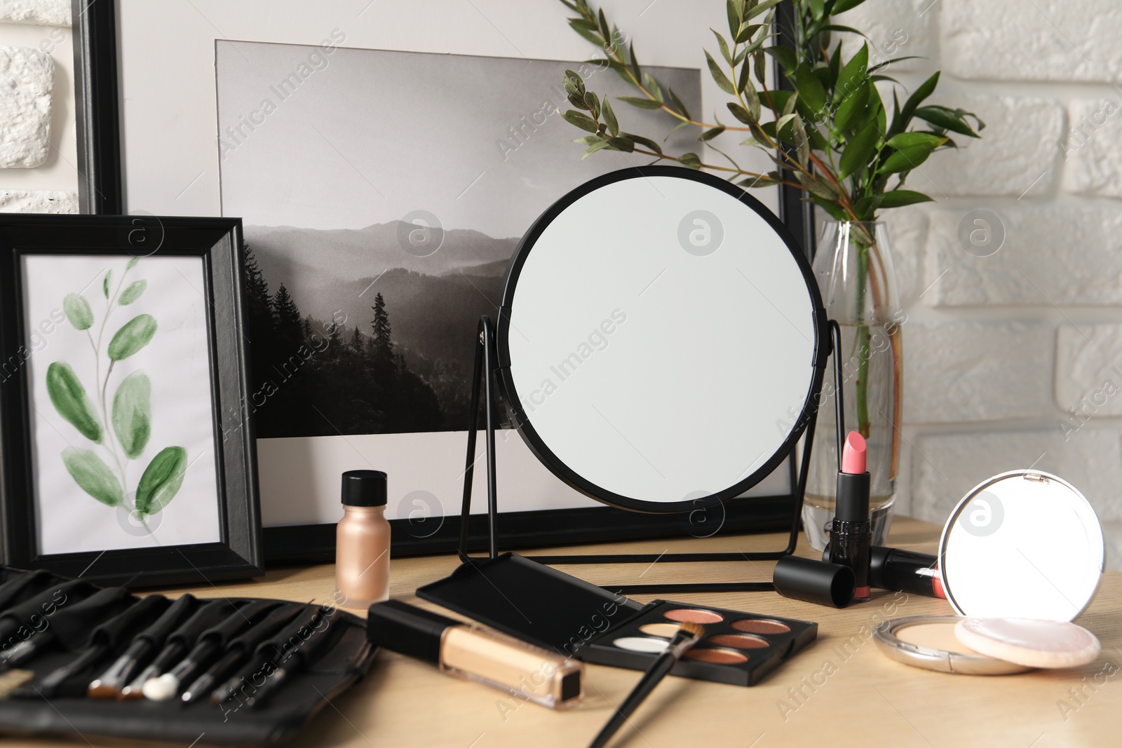 Photo of Mirror and makeup products on wooden dressing table, closeup