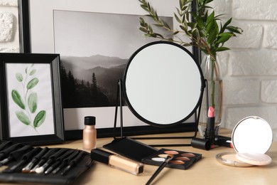 Photo of Mirror and makeup products on wooden dressing table, closeup