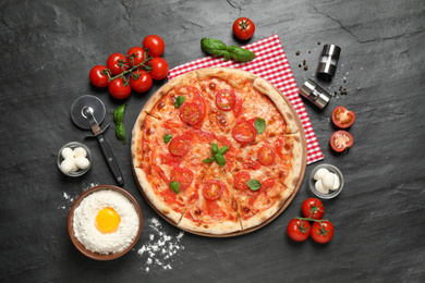 Photo of Delicious pizza Margherita and ingredients on dark grey table, flat lay