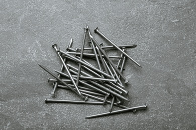 Photo of Pile of metal nails on grey stone background, flat lay