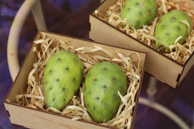 Photo of Delicious fresh ripe opuntia fruits in boxes on wooden table
