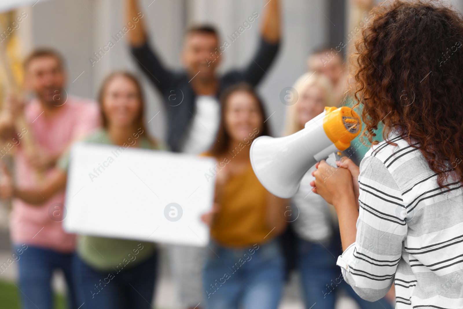 Photo of Female meeting leader with megaphone talking to crowd outdoors