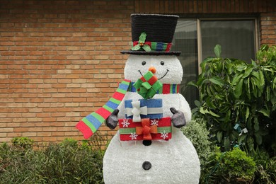 Funny snowman near house outdoors. Festive Christmas decoration