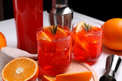 Photo of Aperol spritz cocktail, rosemary and orange slices on white table