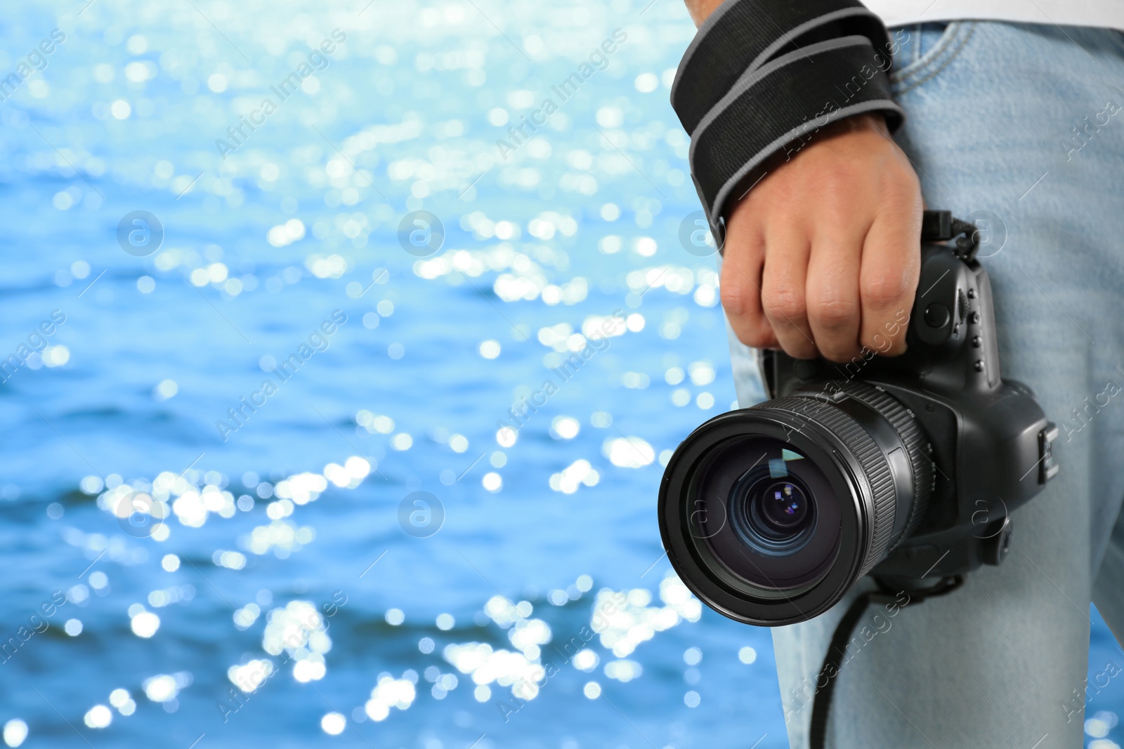 Image of Professional photographer with modern camera and blurred view of beautiful sea on sunny day, space for text