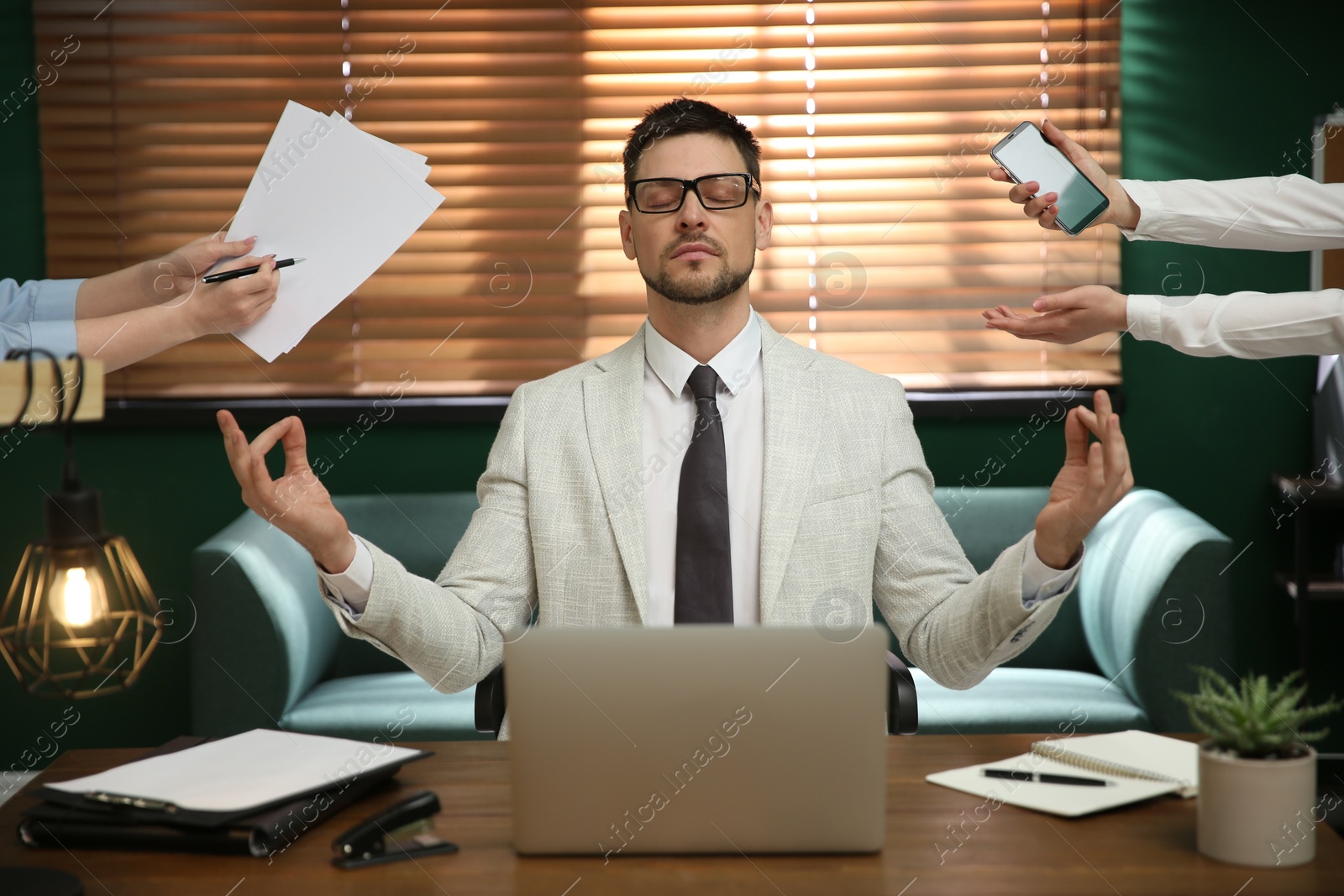 Photo of Calm businessman meditating at office desk in middle of busy work day