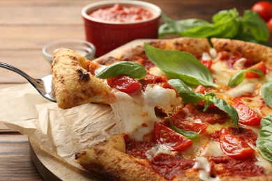 Taking piece of delicious Margherita pizza at wooden table, closeup