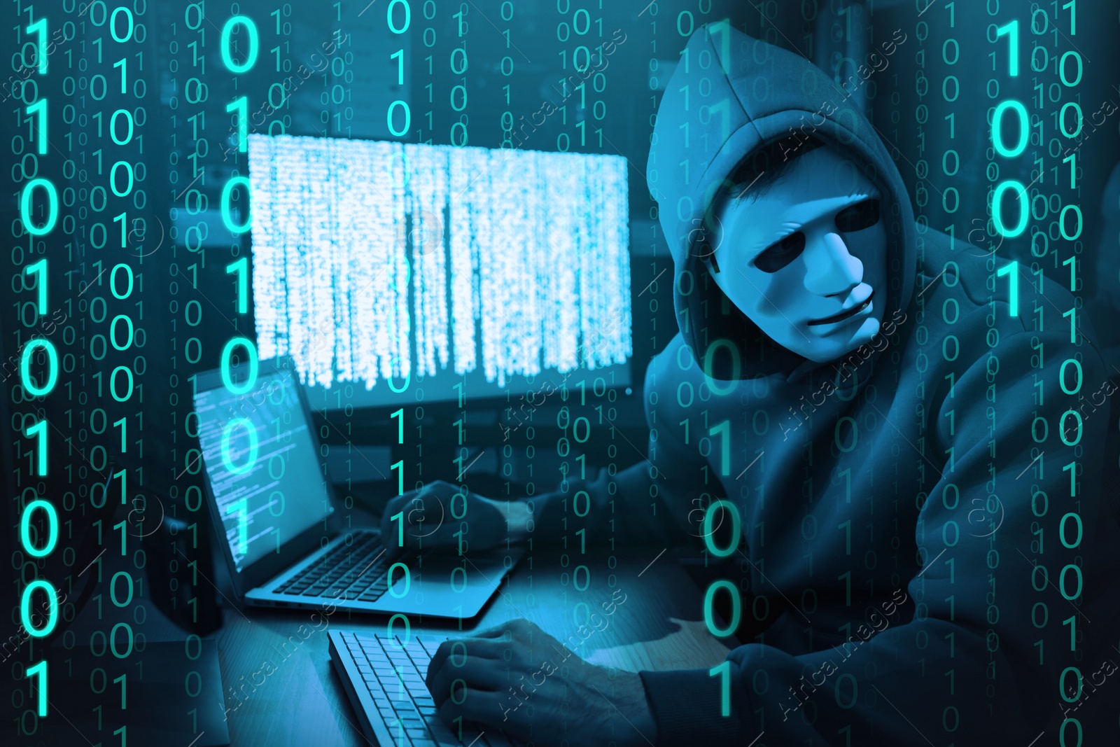 Image of Anonymous man in mask with computers and binary code in darkness