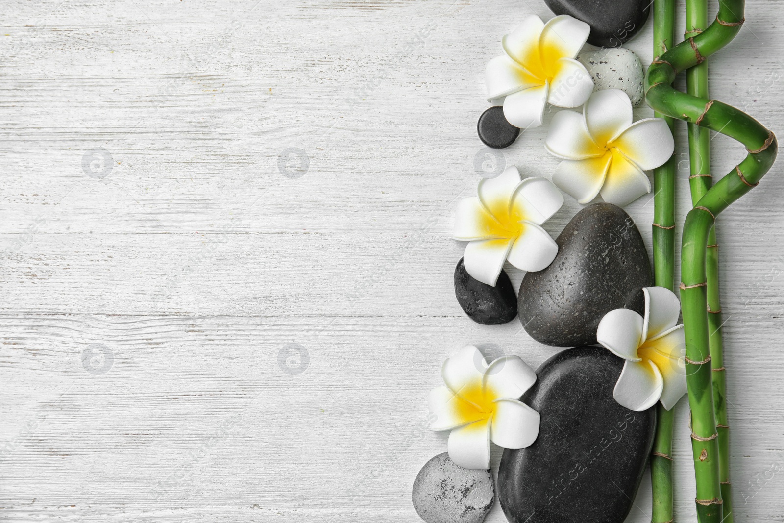 Photo of Flat lay composition with bamboo branches and spa stones on wooden background. Space for text