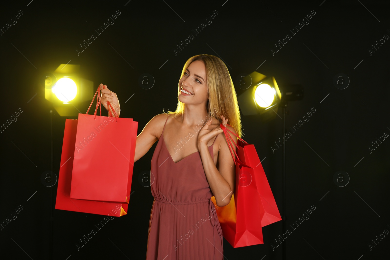 Photo of Happy young woman with shopping bags on dark background. Black Friday Sale