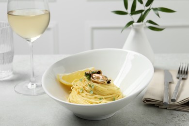 Tasty capellini with mussels and lemon served on light grey table. Exquisite presentation of pasta dish