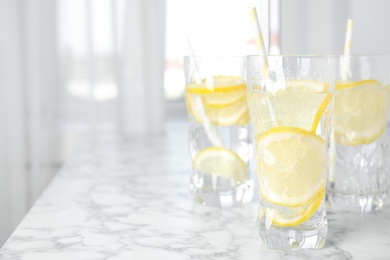 Soda water with lemon slices on white marble table. Space for text