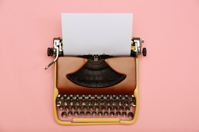 Photo of Vintage typewriter with sheet of paper on pink background, top view