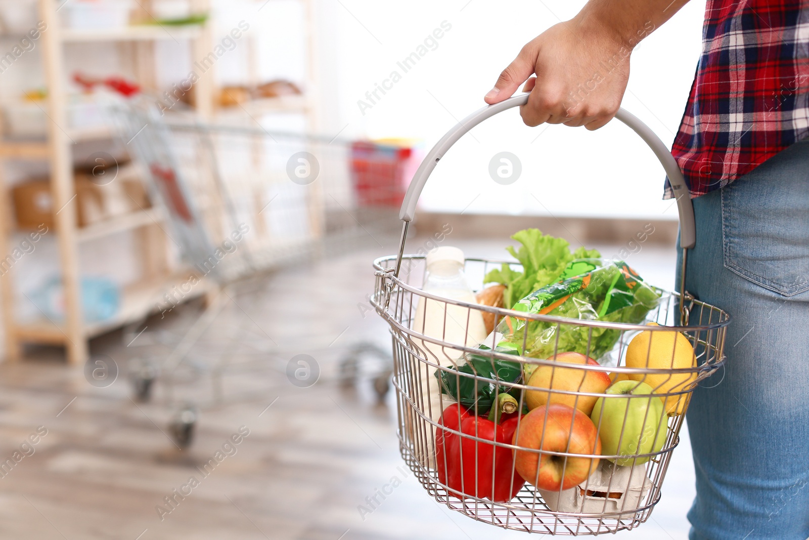 Photo of Man with shopping basket full of products in grocery store, closeup