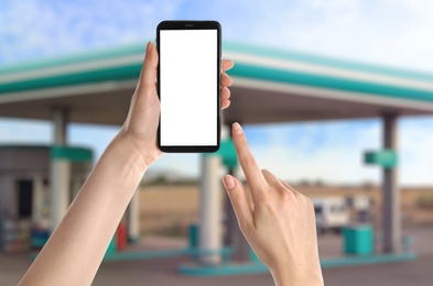 Image of Woman paying for refueling via smartphone at gas station, closeup. Device with empty screen