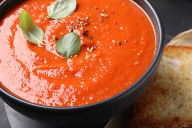 Photo of Delicious tomato cream soup on black table, closeup