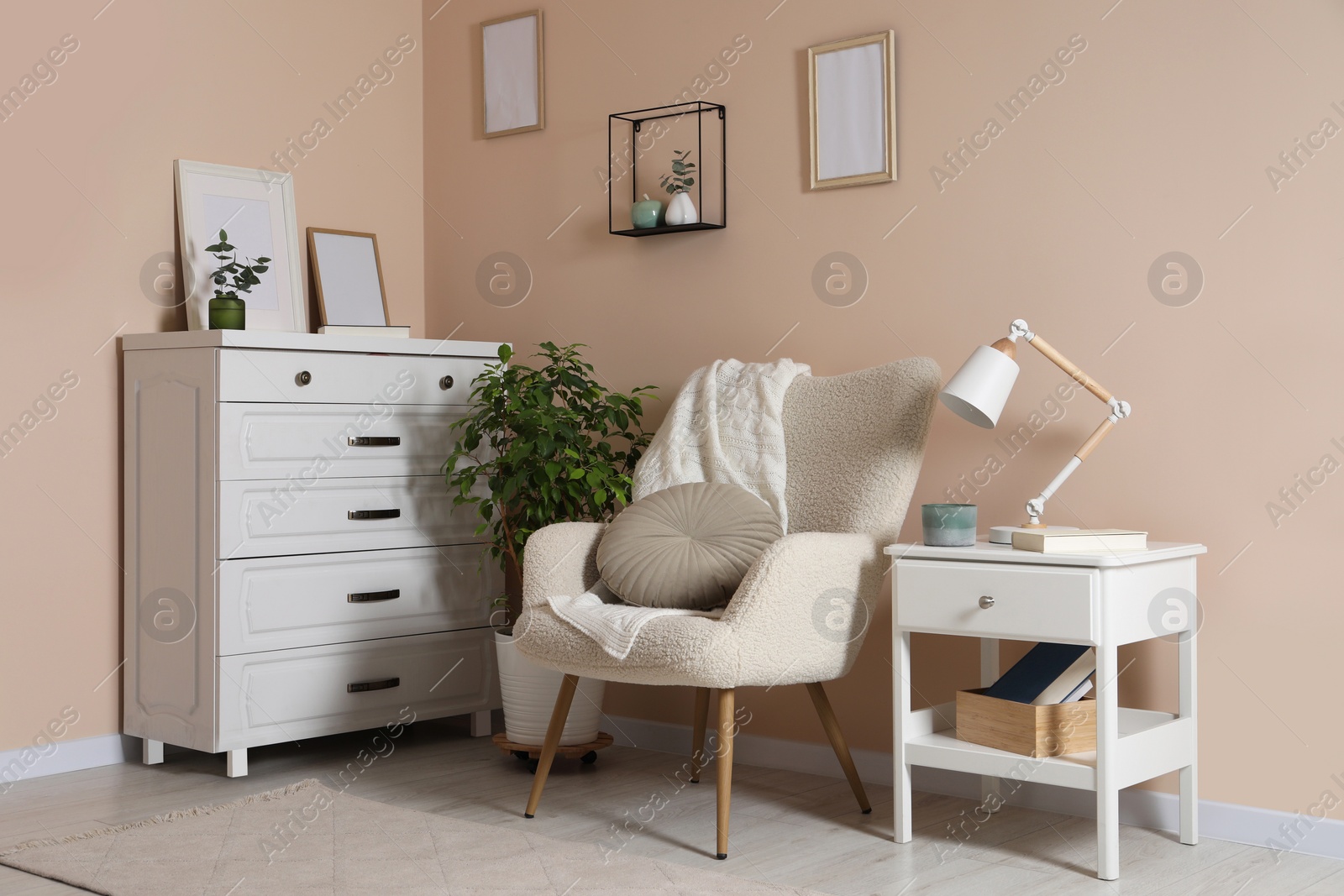 Photo of Cozy room interior with stylish white furniture, desk lamp and beautiful decor elements