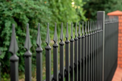 Photo of Beautiful brick fence with iron railing outdoors, closeup