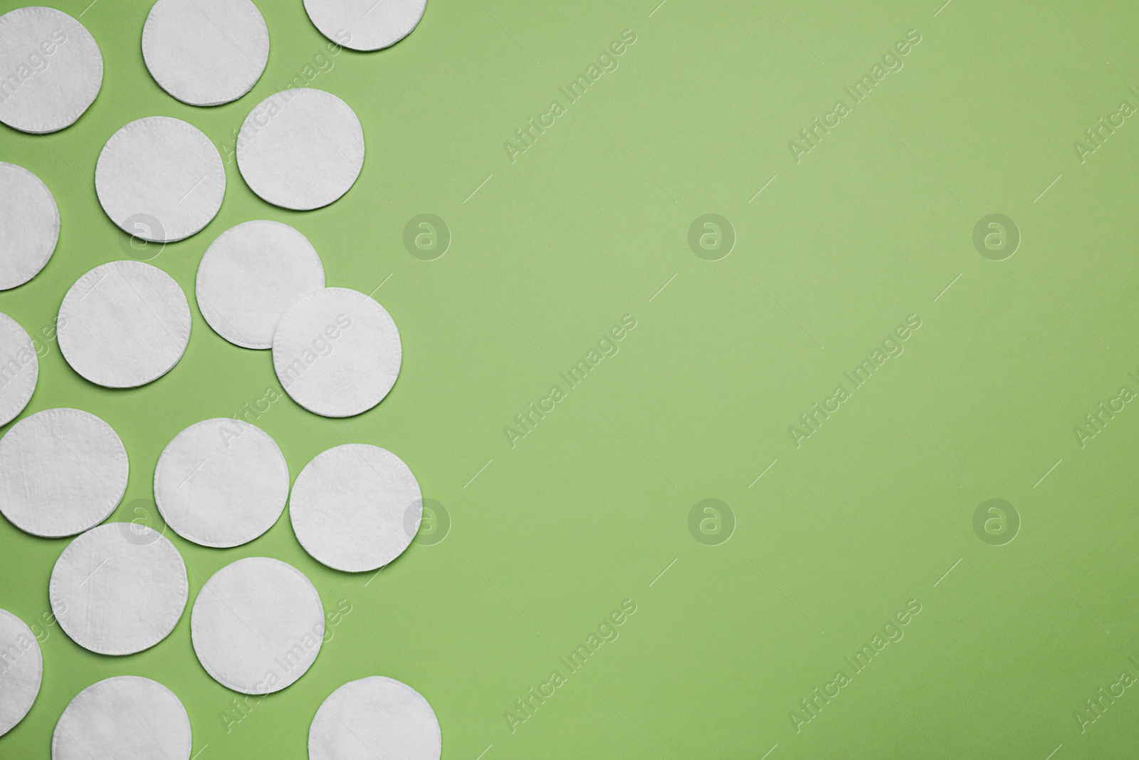 Photo of Many cotton pads on green background, flat lay. Space for text