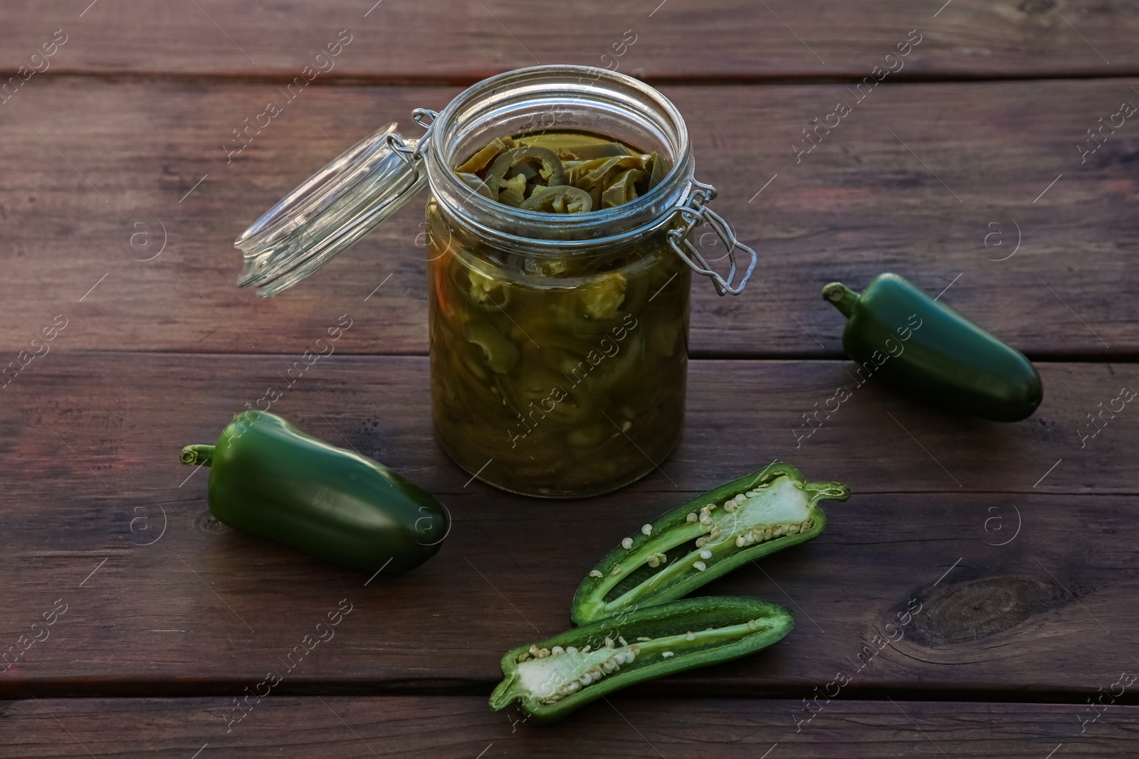 Photo of Fresh and pickled green jalapeno peppers on wooden table