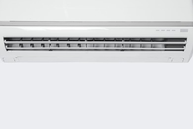 Photo of Modern air conditioner on white wall. Space for text