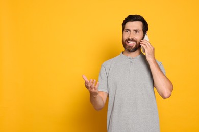 Photo of Happy man talking on phone against yellow background. Space for text