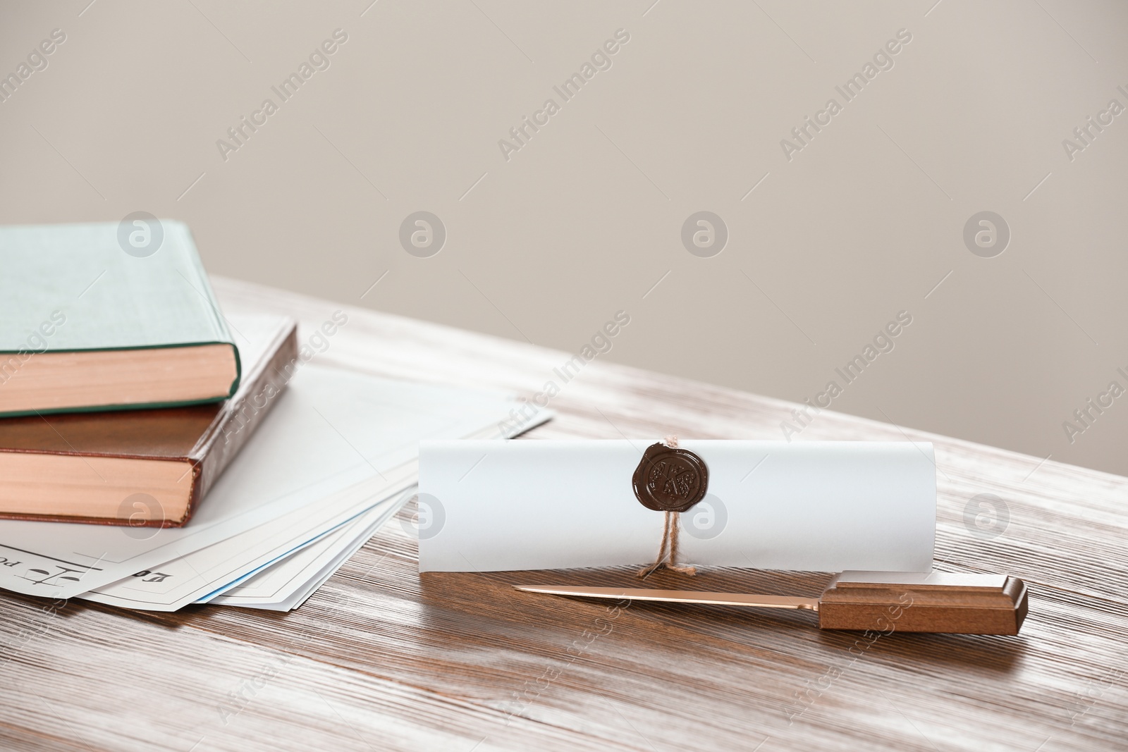 Photo of Scroll with notary seal, books, documents and letter opener on wooden table. Space for text