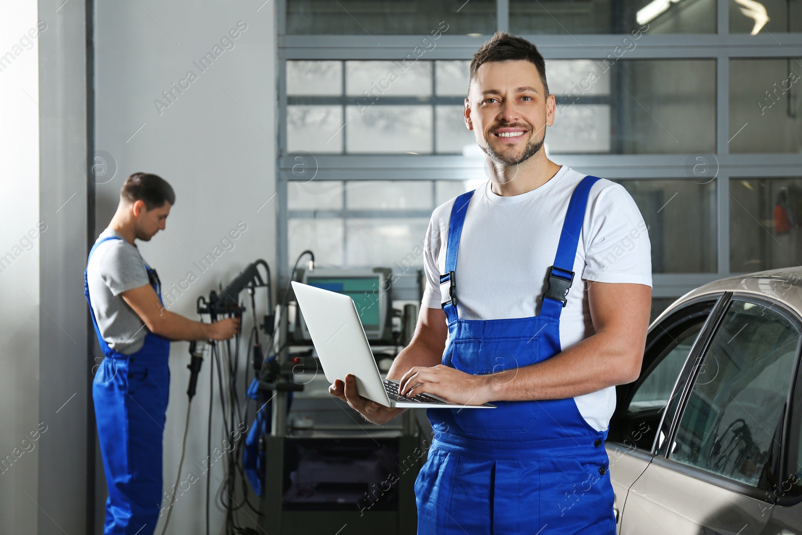 Photo of Mechanic with laptop doing car diagnostic at automobile repair shop