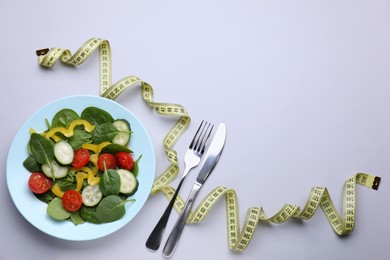 Measuring tape, salad and cutlery on light background, flat lay. Space for text