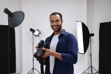 Photo of Young professional photographer with camera in modern photo studio