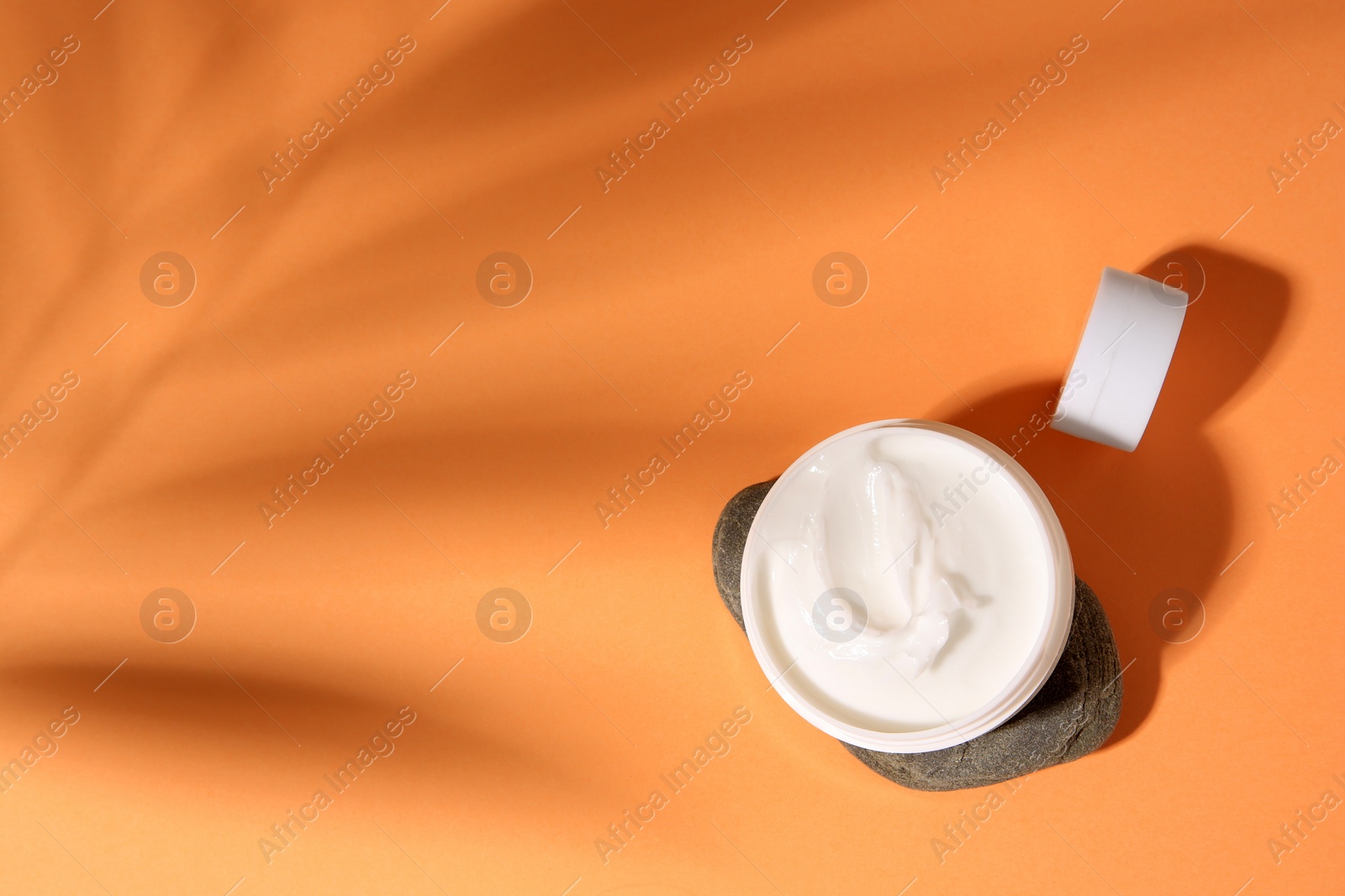 Photo of Cosmetic products and spa stone on orange background, flat lay. Space for text