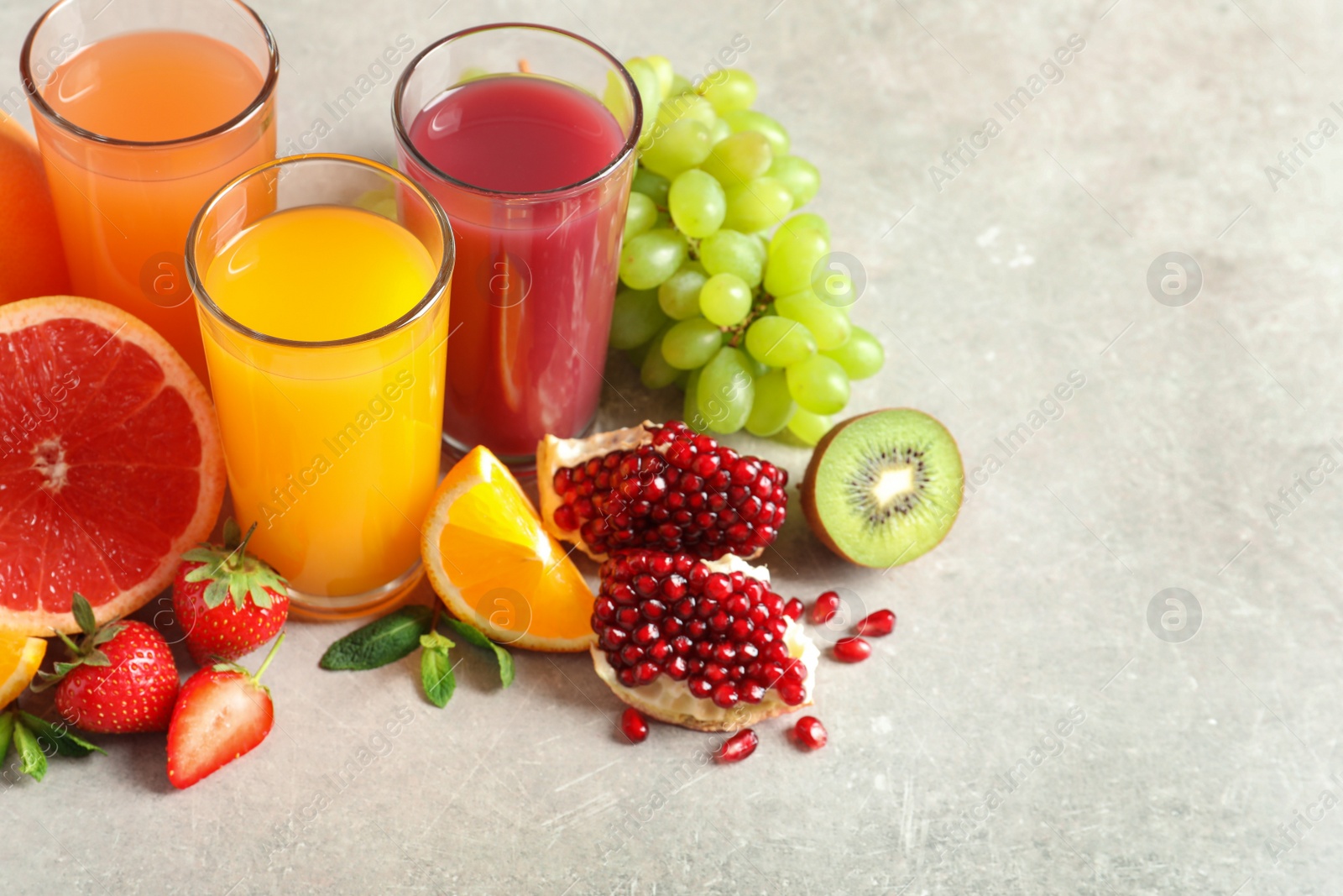 Photo of Glasses of different juices and fresh fruits on table. Space for text