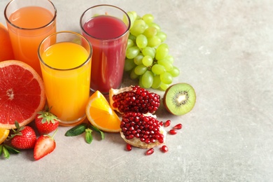 Photo of Glasses of different juices and fresh fruits on table. Space for text