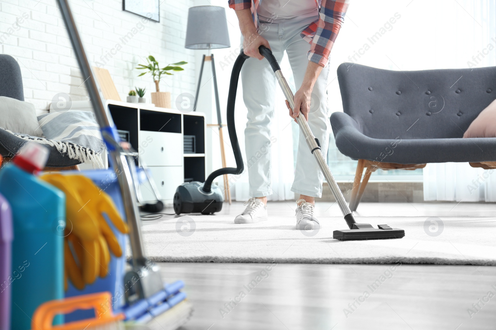 Photo of Janitor hoovering carpet with vacuum cleaner indoors, closeup