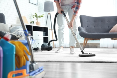 Photo of Janitor hoovering carpet with vacuum cleaner indoors, closeup