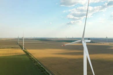 Photo of Modern windmill in field, space for text. Energy efficiency