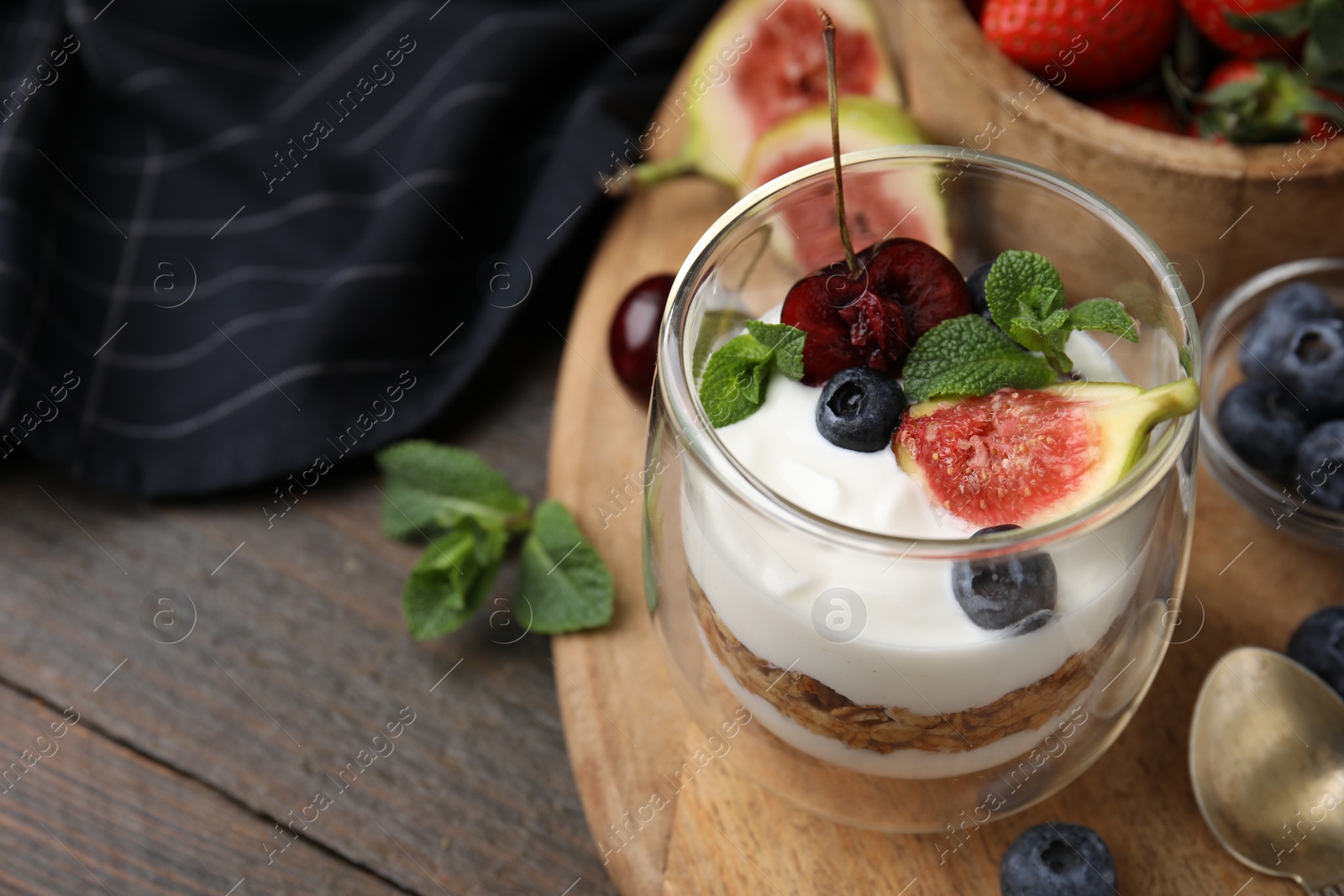 Photo of Glass with yogurt, berries and mint on wooden table, closeup. Space for text